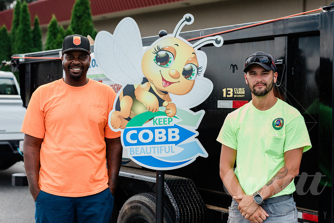 Two male employees of Keep Cobb Beautiful stand outside ready to retrieve recyclables, outside the Cobb Civic Center during the School Supply Drive hosted by KIDS CARE.  