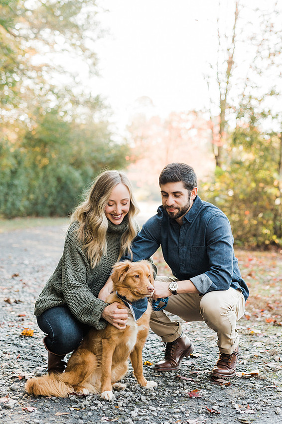 couple smiles with their dog, at a park
