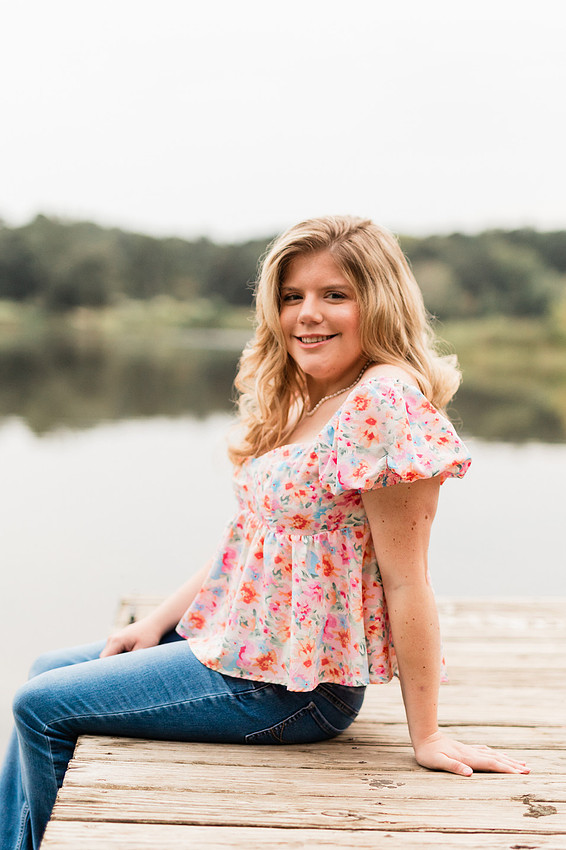 Senior in high school poses for senior session on a dock. 
