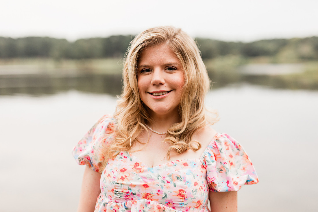Senior in high school poses for senior session on a dock. 