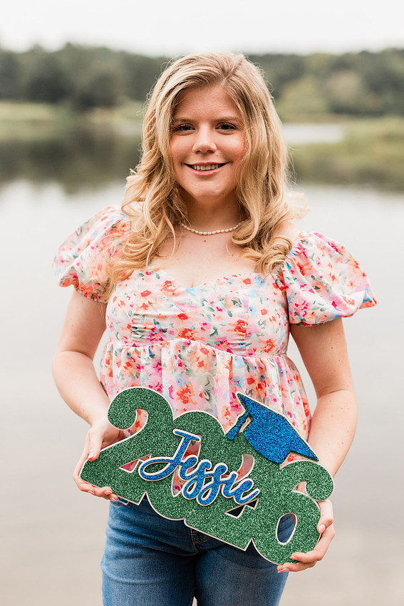 Senior in high school poses for senior session on a dock. 