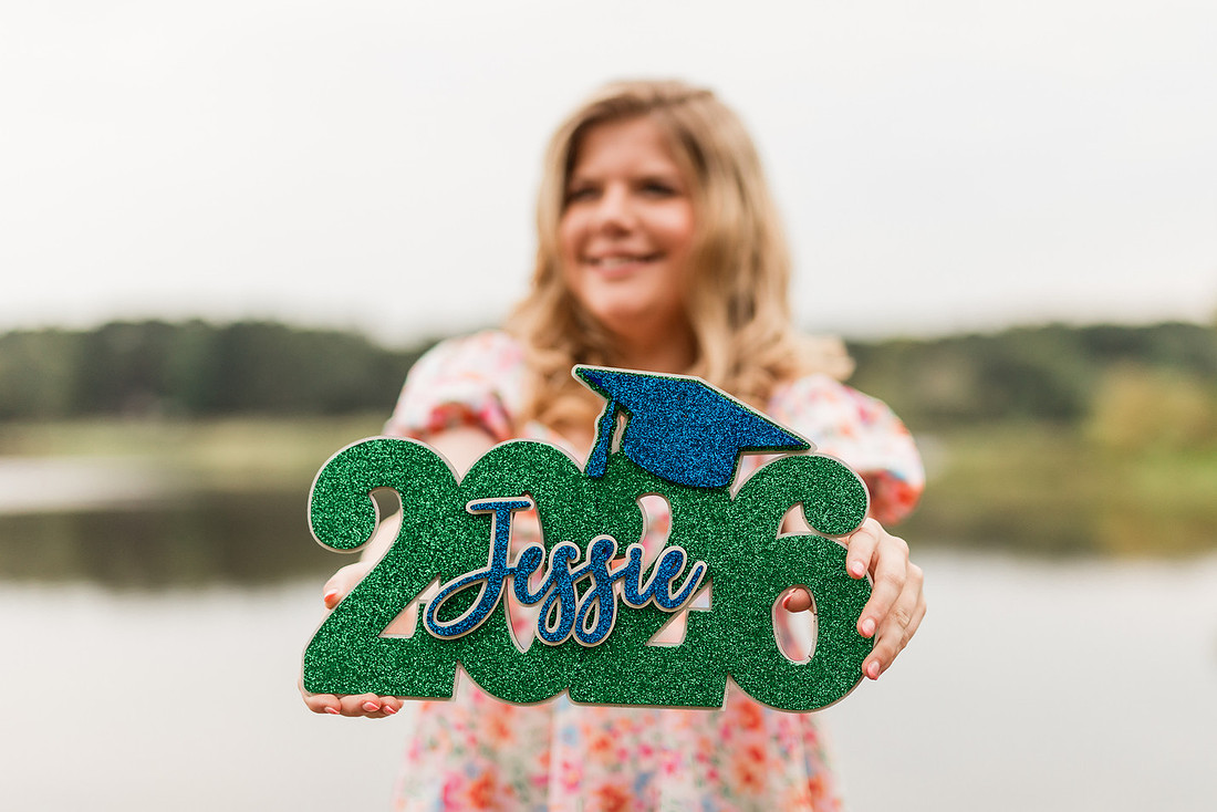 Senior in high school poses for senior session on a dock. 