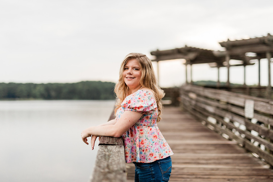 Senior in high school poses for senior session on a dock. 
