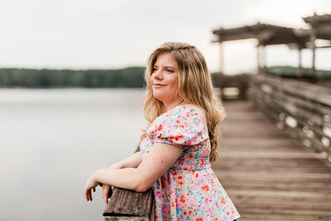 Senior in high school poses for senior session on a dock. 