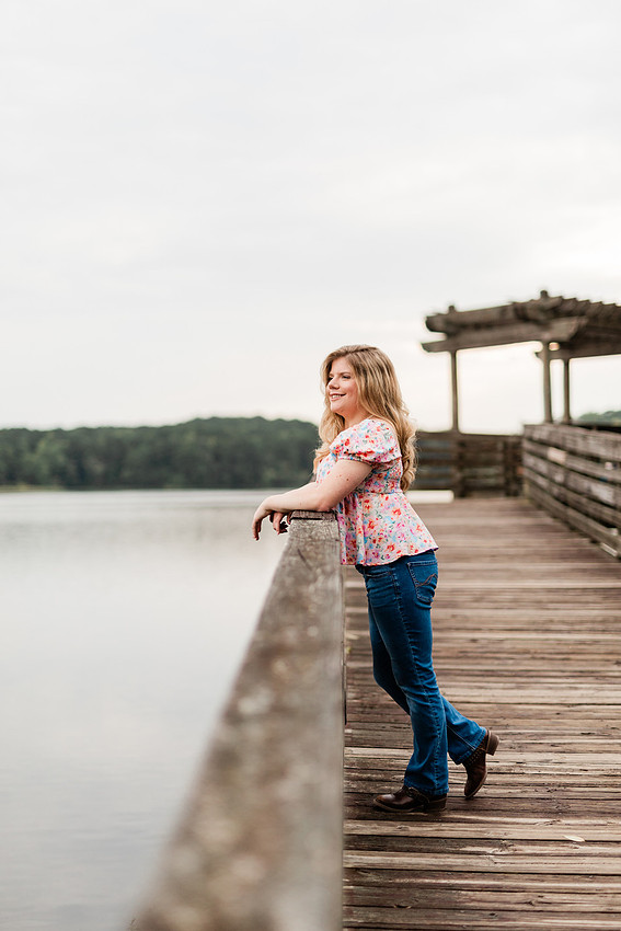 Senior in high school poses for senior session on a dock. 