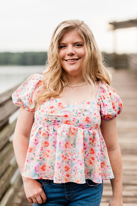 Senior in high school poses for senior session on a dock. 