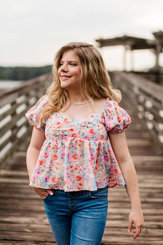 Senior in high school poses for senior session on a dock. 