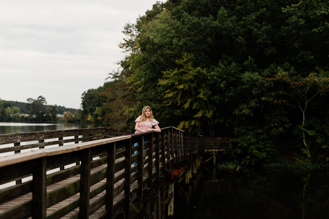Senior in high school poses for senior session on a dock. 