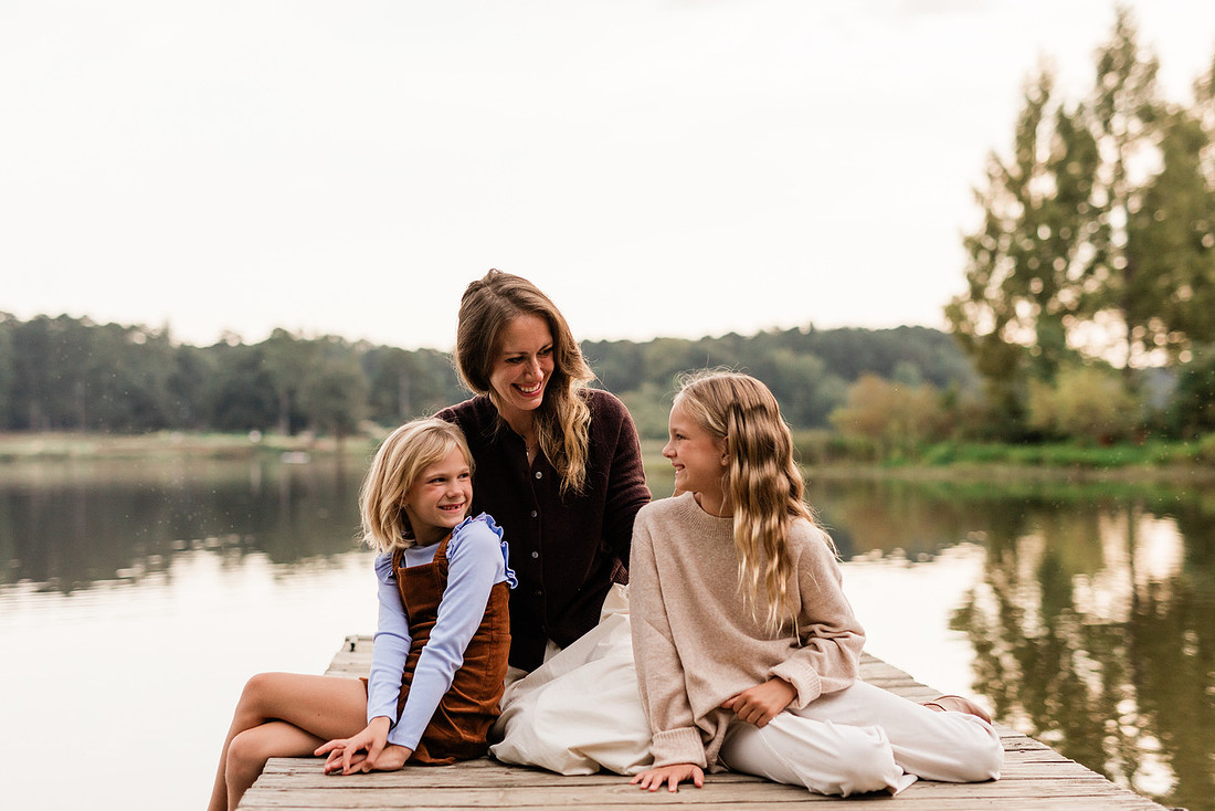Family posing on a dock surrounded by calm lake water and soft evening light.