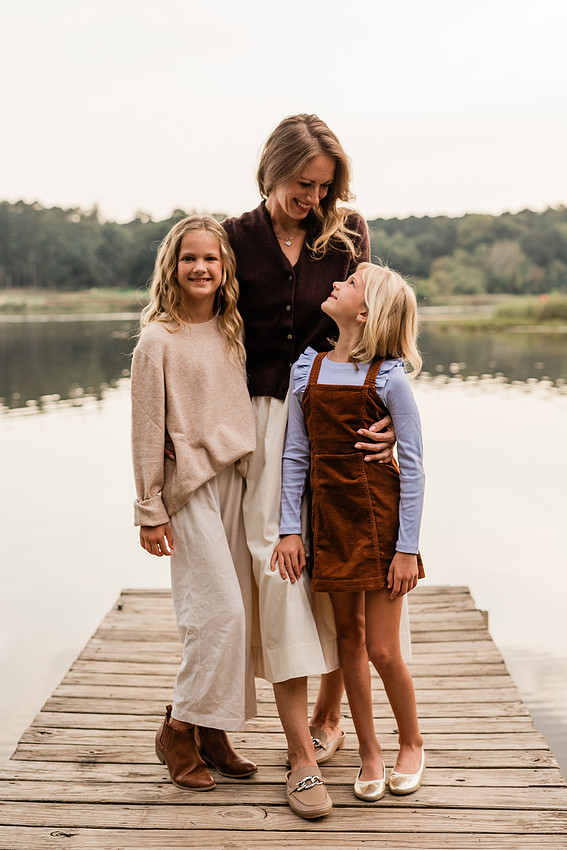 Family posing on a dock surrounded by calm lake water and soft evening light.