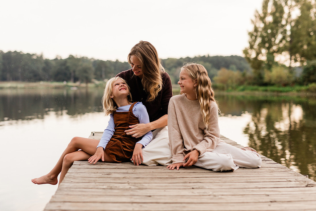 Family posing on a dock surrounded by calm lake water and soft evening light.