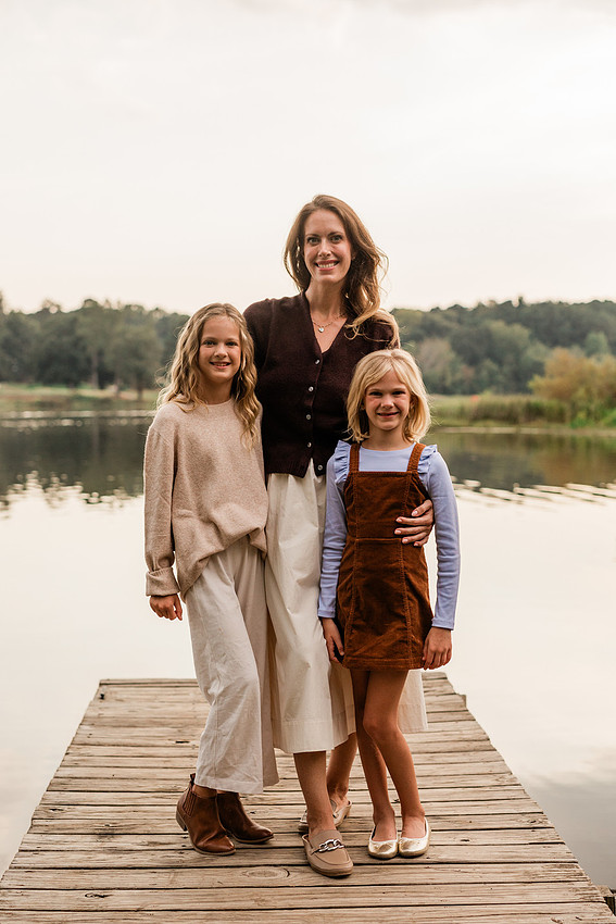 Family posing on a dock surrounded by calm lake water and soft evening light.