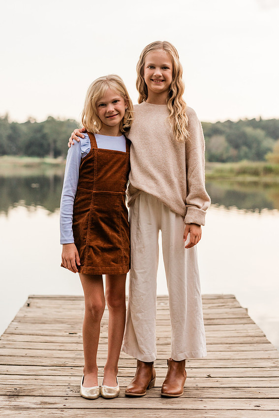Family posing on a dock surrounded by calm lake water and soft evening light.