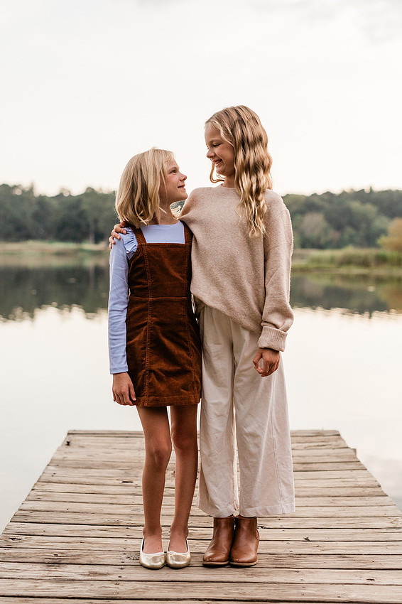 Family posing on a dock surrounded by calm lake water and soft evening light.