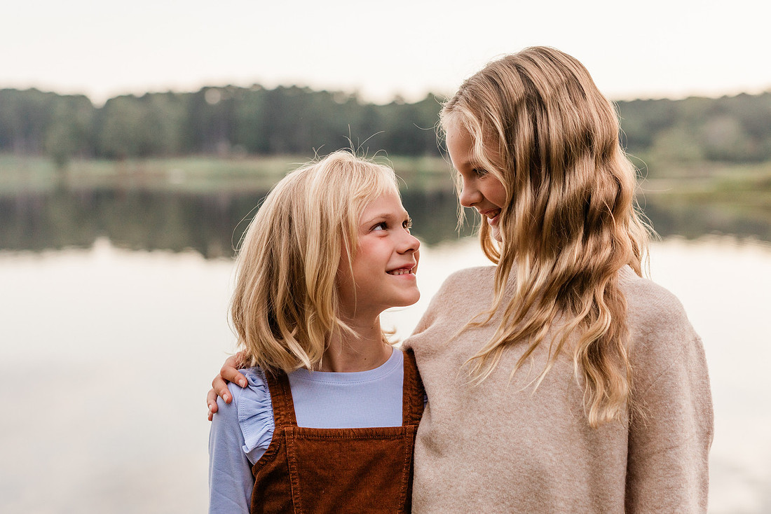Family posing on a dock surrounded by calm lake water and soft evening light.