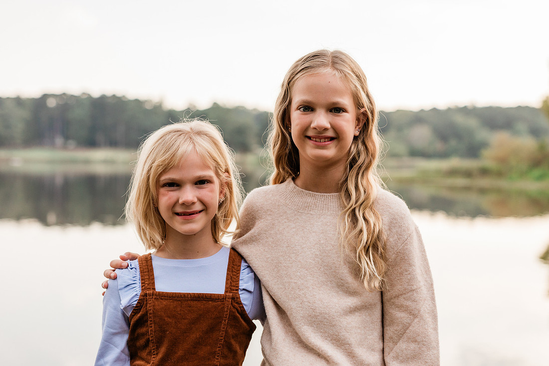 Family posing on a dock surrounded by calm lake water and soft evening light.