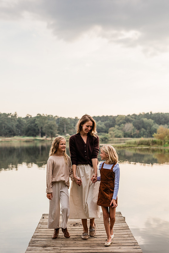 Family posing on a dock surrounded by calm lake water and soft evening light.