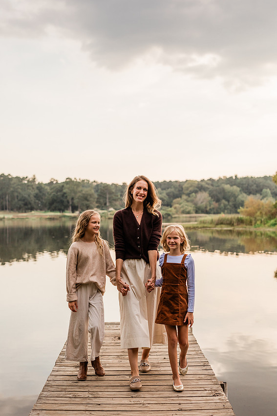 Family posing on a dock surrounded by calm lake water and soft evening light.