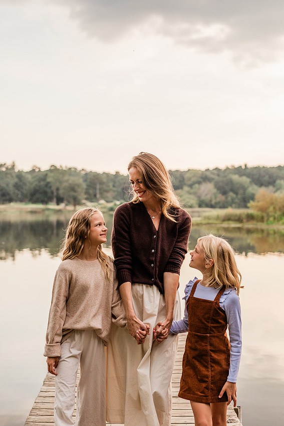 Family posing on a dock surrounded by calm lake water and soft evening light.