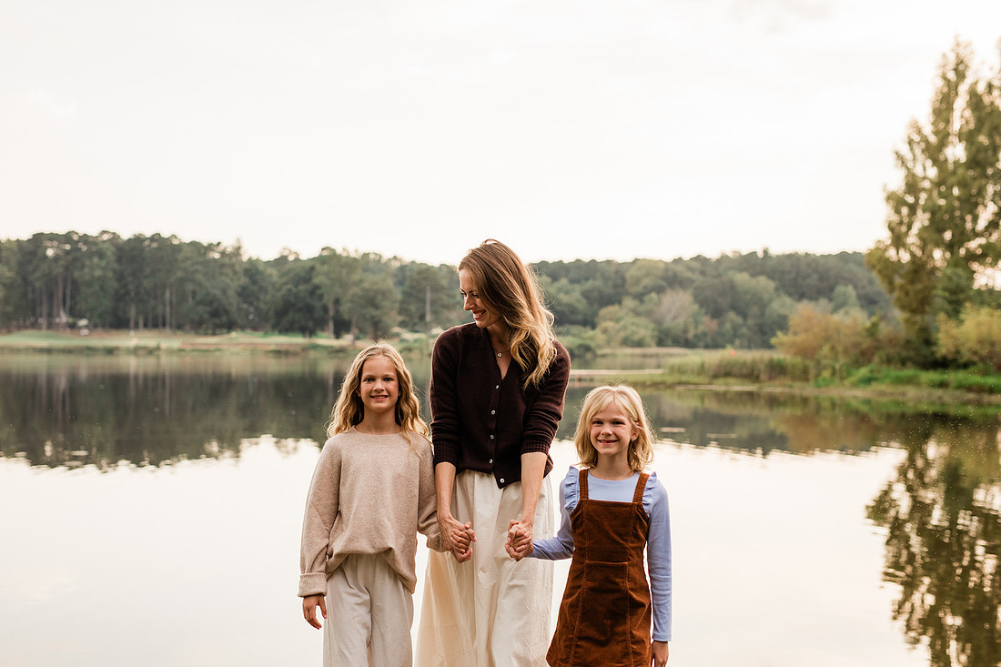 Family posing on a dock surrounded by calm lake water and soft evening light.