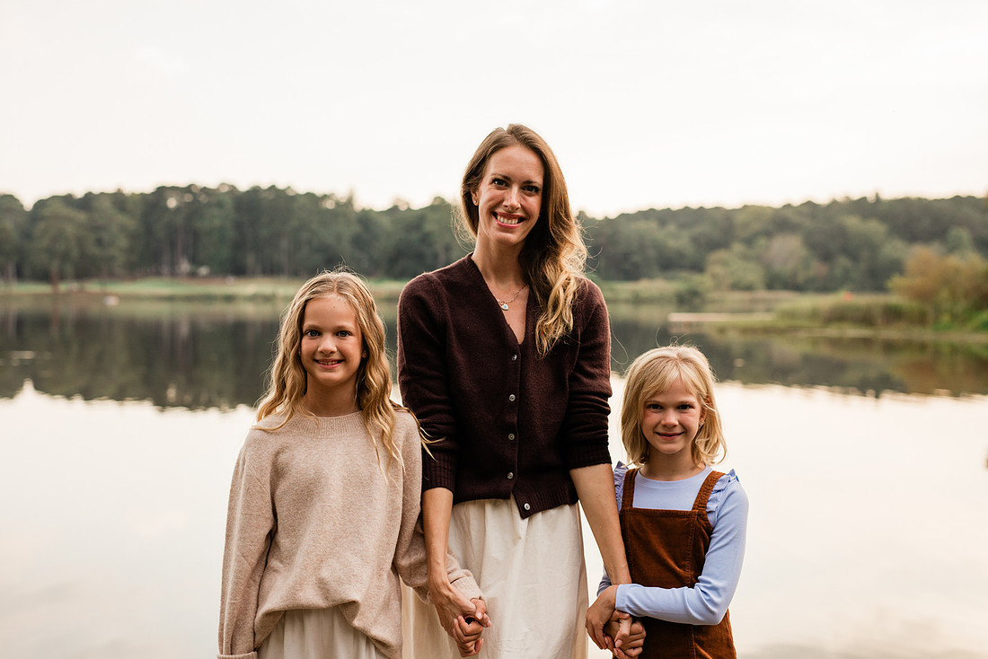 Family posing on a dock surrounded by calm lake water and soft evening light.