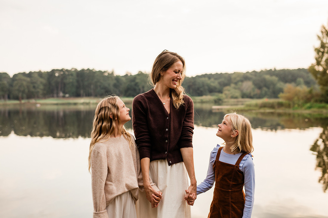 Family posing on a dock surrounded by calm lake water and soft evening light.