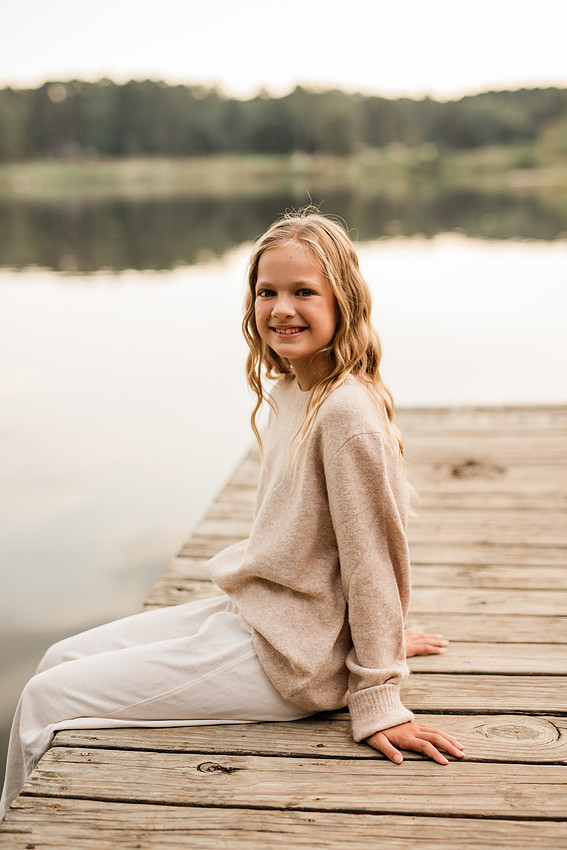 Family posing on a dock surrounded by calm lake water and soft evening light.