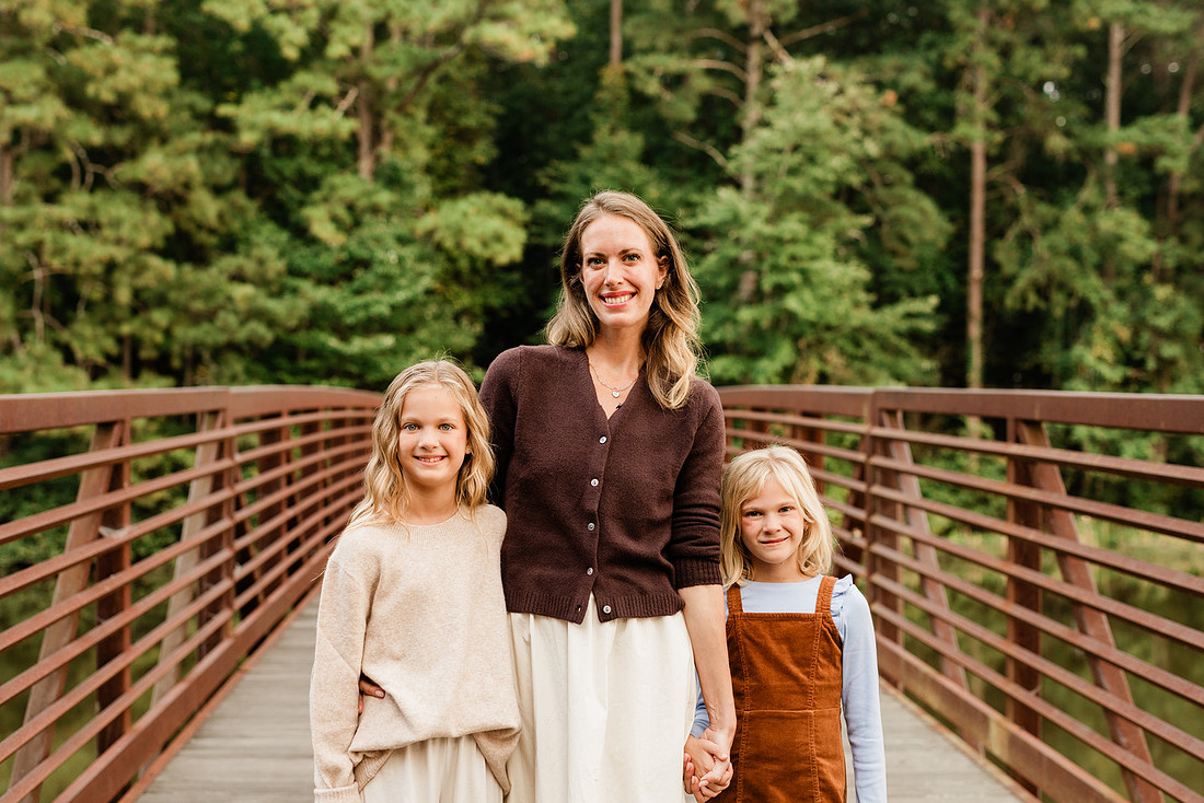 Family posing on a dock surrounded by calm lake water and soft evening light.