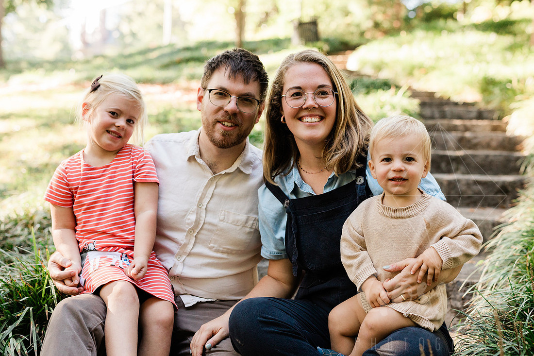 Family exploring a forest trail during a mini session, capturing playful, candid moments.