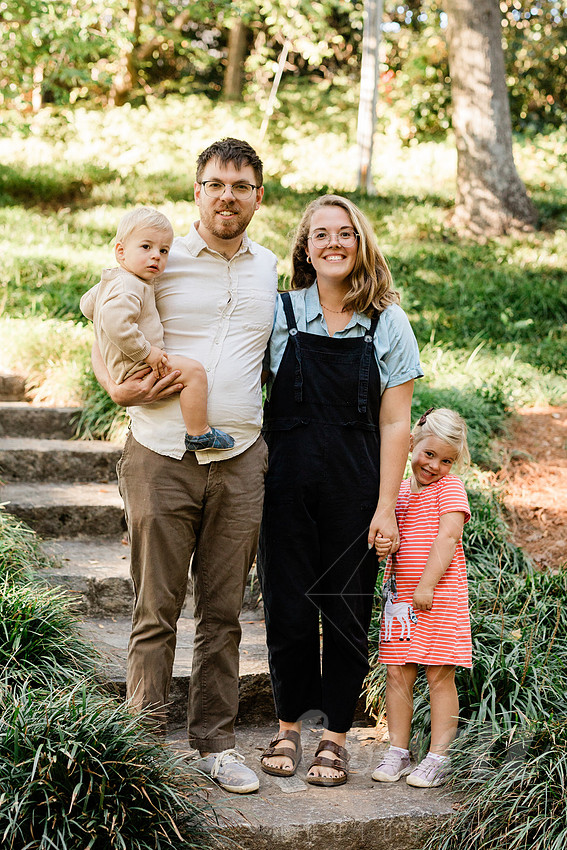 Family exploring a forest trail during a mini session, capturing playful, candid moments.