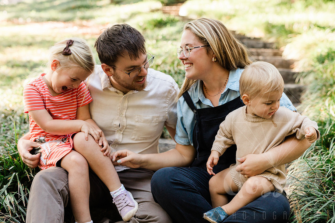 Family exploring a forest trail during a mini session, capturing playful, candid moments.