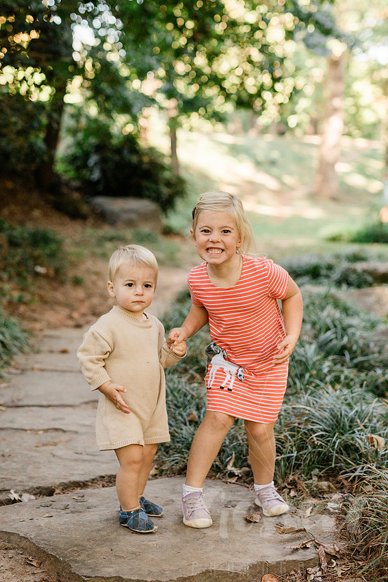 Family exploring a forest trail during a mini session, capturing playful, candid moments.