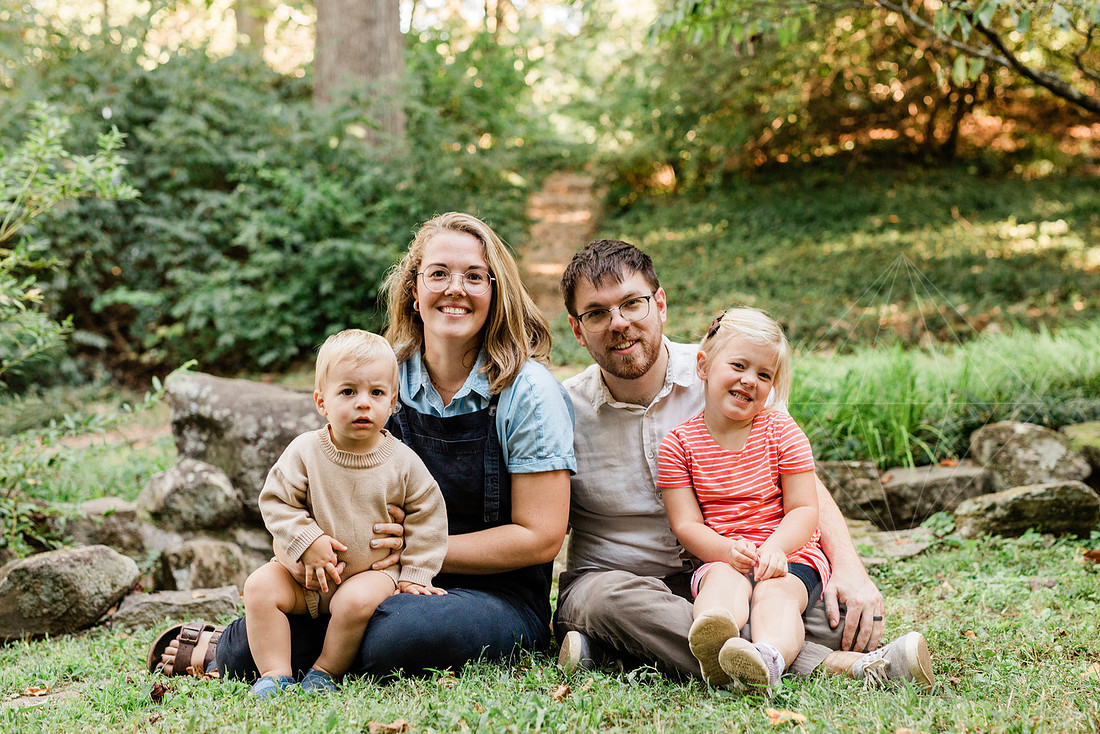 Family exploring a forest trail during a mini session, capturing playful, candid moments.