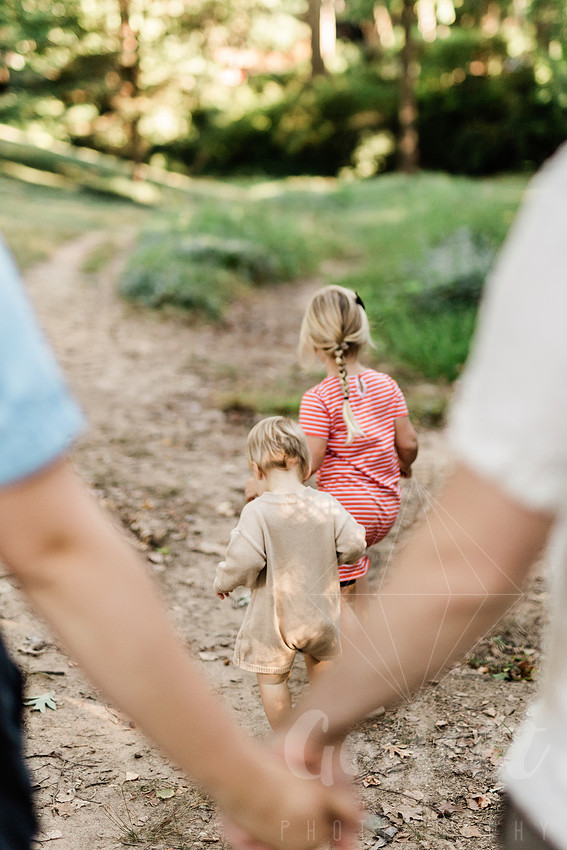 Family exploring a forest trail during a mini session, capturing playful, candid moments.