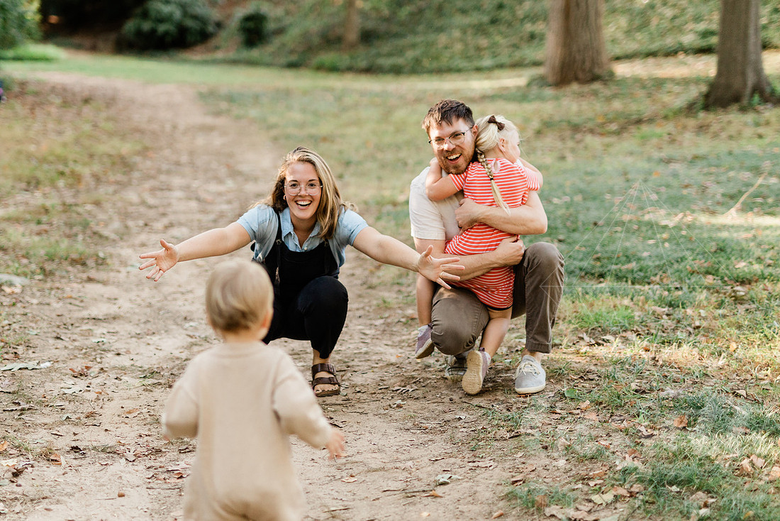 Family exploring a forest trail during a mini session, capturing playful, candid moments.
