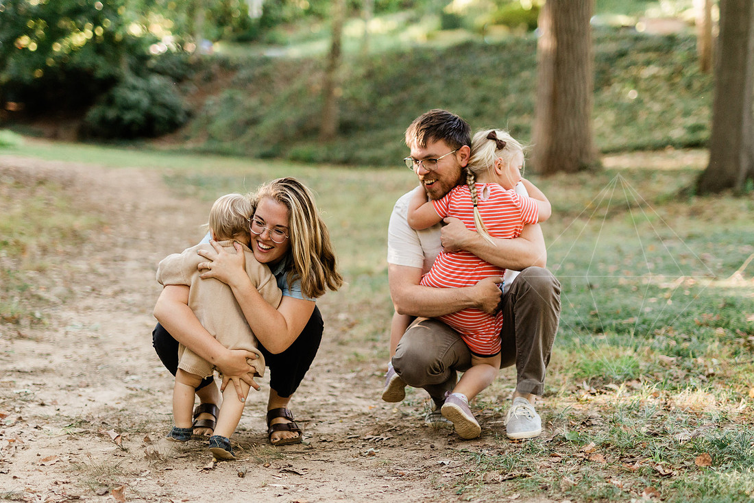 Family exploring a forest trail during a mini session, capturing playful, candid moments.