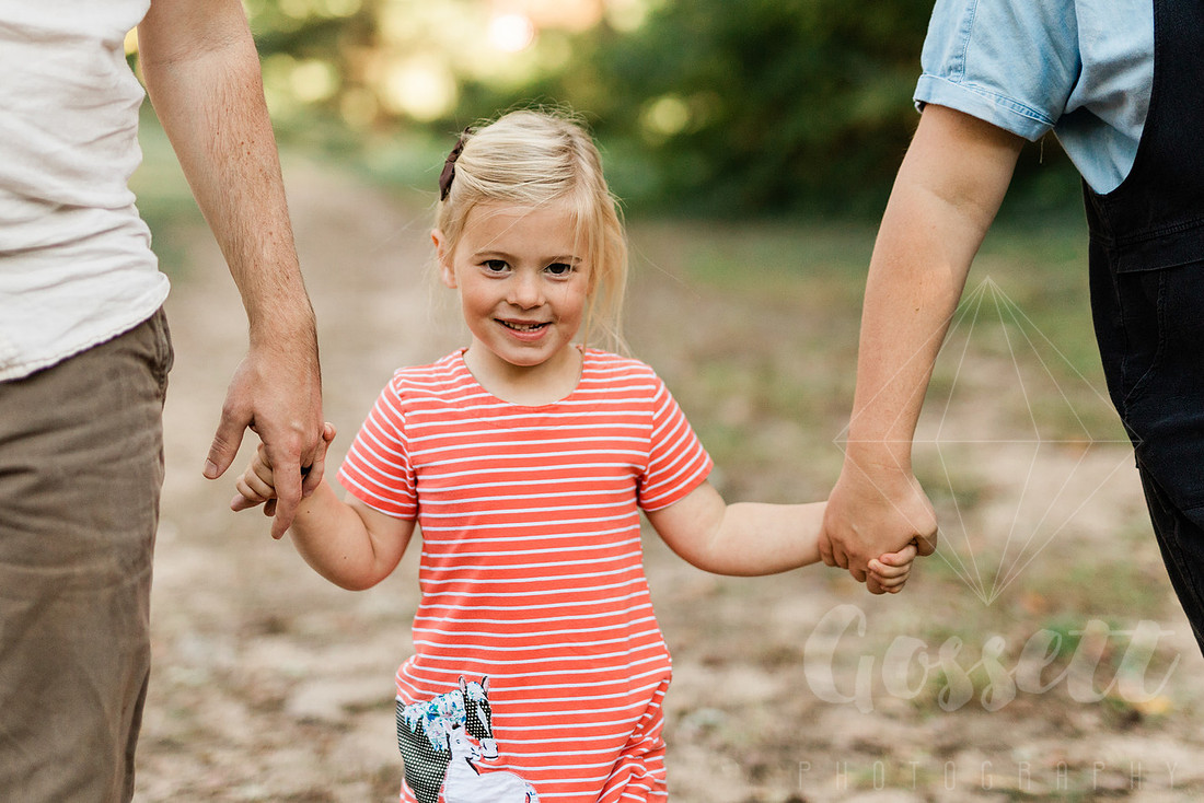 Family exploring a forest trail during a mini session, capturing playful, candid moments.