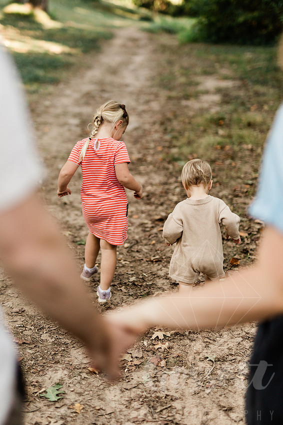 Family exploring a forest trail during a mini session, capturing playful, candid moments.