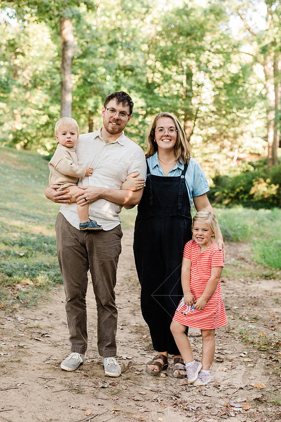 Family exploring a forest trail during a mini session, capturing playful, candid moments.