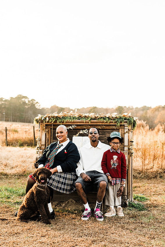 Family gathered around a vintage piano in a golden field for a holiday session. 