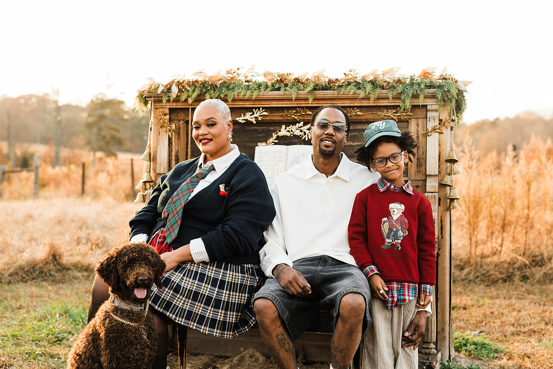 Family gathered around a vintage piano in a golden field for a holiday session. 