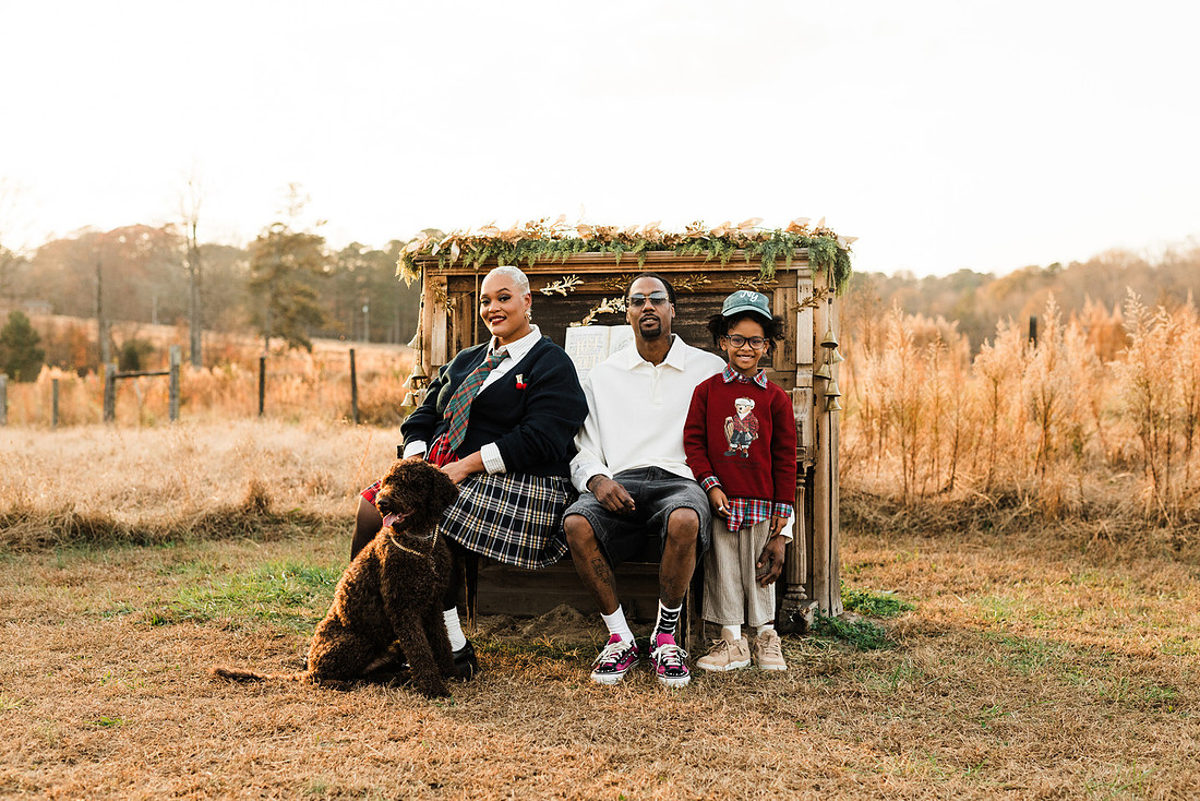 Family gathered around a vintage piano in a golden field for a holiday session. 