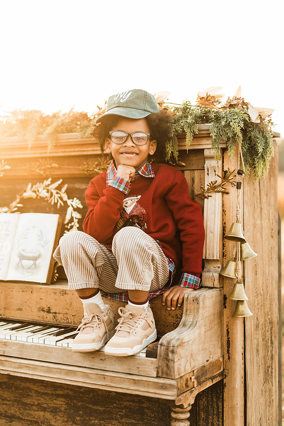 Family gathered around a vintage piano in a golden field for a holiday session. 