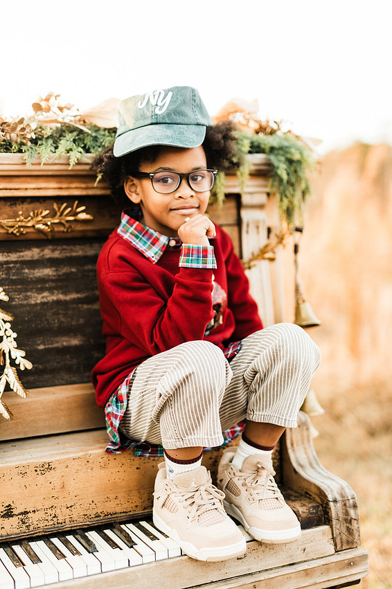 Family gathered around a vintage piano in a golden field for a holiday session. 