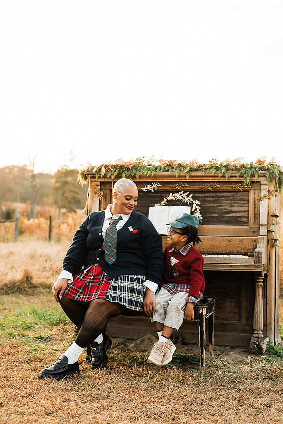 Family gathered around a vintage piano in a golden field for a holiday session. 
