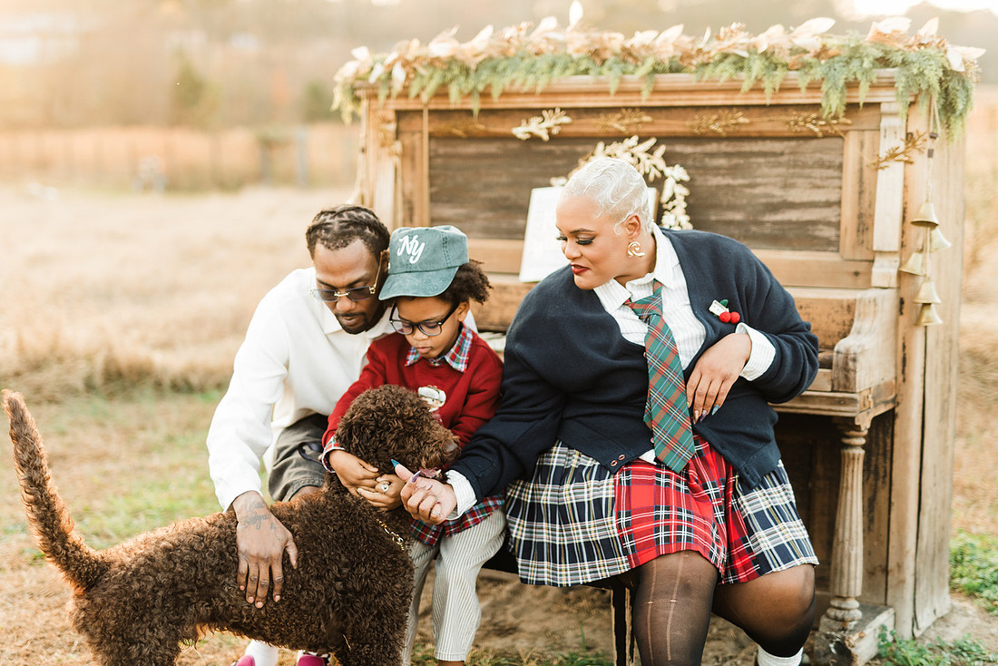Family gathered around a vintage piano in a golden field for a holiday session. 