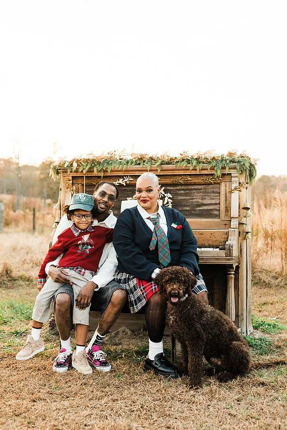 Family gathered around a vintage piano in a golden field for a holiday session. 