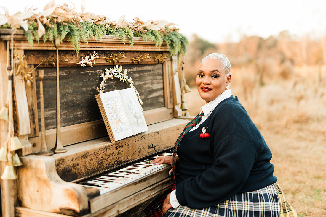Family gathered around a vintage piano in a golden field for a holiday session. 