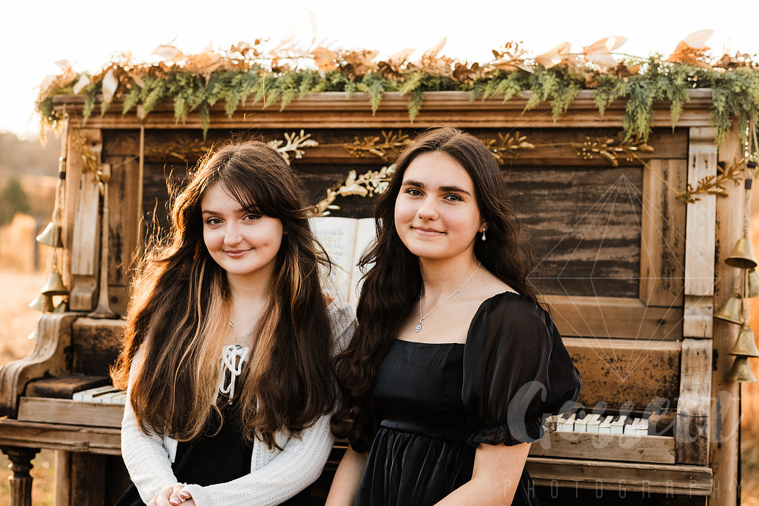 a family gathers around a vintage piano in a golden field for a christmas mini session