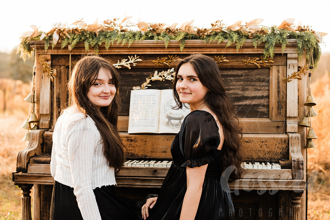 a family gathers around a vintage piano in a golden field for a christmas mini session